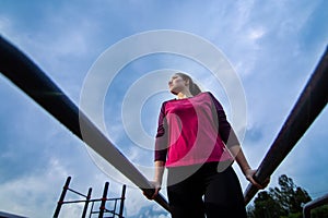 Strong Young woman goes sports outside. Lady pulling up in workout area.