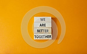 We are stronger better symbol. Wooden blocks with words We are better together. Beautiful orange background. We are stronger