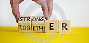 Stronger together symbol. Businessman turns cubes and changes the word together to stronger. Beautiful yellow table, white