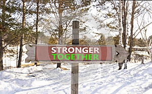 Stronger together symbol. Concept words Stronger together on beautiful wooden road sign. Beautiful forest snow blue sky background
