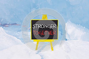 Stronger together symbol. Concept words Stronger together on beautiful yellow black blackboard. Beautiful blue ice background.