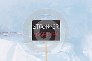 Stronger together symbol. Concept words Stronger together on beautiful yellow black blackboard. Beautiful blue ice background.