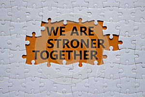 We are stronger together symbol. White puzzle with words We are stronger together. Beautiful orange background. We are stronger
