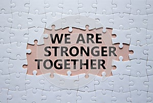 We are stronger together symbol. White puzzle with words We are stronger together. Beautiful pink background. We are stronger