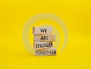 We are stronger together symbol. Wooden blocks with words We are stronger together. Beautiful yellow background. We are stronger