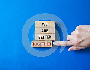 We are stronger together symbol. Wooden blocks with words We are stronger together. Businessman hand. Beautiful blue background.