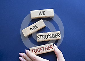 We are stronger together symbol. Wooden blocks with words We are stronger together. Businessman hand. Beautiful deep blue