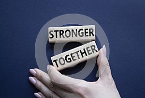 Stronger together symbol. Wooden blocks with words Stronger together. Businessman hand. Beautiful deep blue background. Stronger