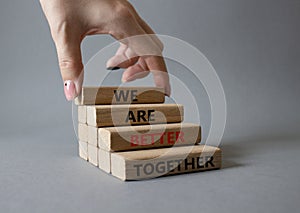 We are stronger together symbol. Wooden blocks with words We are stronger together. Businessman hand. Beautiful grey background.
