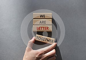 We are stronger together symbol. Wooden blocks with words We are stronger together. Businessman hand. Beautiful grey background.