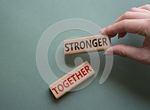 Stronger together symbol. Wooden blocks with words Stronger together. Businessman hand. Beautiful grey green background. Stronger