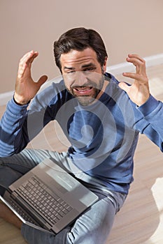 Strssed man sitting on floor using laptop