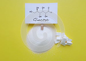 Structural chemical formula of glucose molecule. Refined crystalline sugar and cube sugar on yellow background