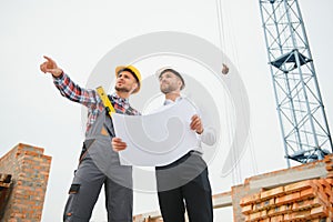 Structural engineer and foreman worker discuss, plan working for the outdoors building construction site