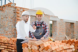 Structural engineer and foreman worker discuss, plan working for the outdoors building construction site