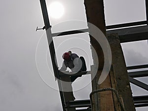 A structural steel worker working on a high rooftop for a house roof structure installation