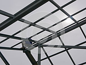 A structural steel worker working on a high rooftop for a house roof structure installation