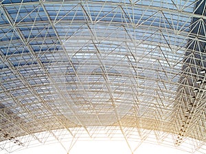 Structural white steel frame inside arched roof with evening sunlight