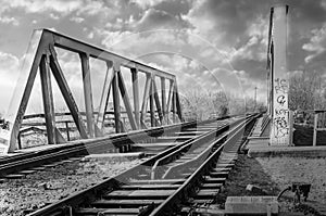 Structure of gray metal railway bridge for train in a sunny day. Old railway bridge over the water, in black and white