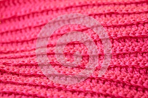The structure of a knitted canvas of pink wool threads.