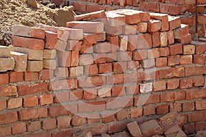 A structure of orange bricks and the unconstructed wall of low quality construction material.