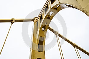 Structure of a self anchored suspension bridge seen from below painted yellow