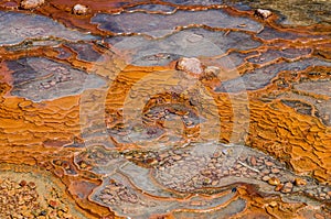 Structure of surface around orange mineral pool of natural water spring in Damia, Morocco, Africa