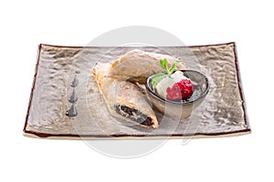 Strudel dessert with plum and ice cream on grey plate isolated on white background