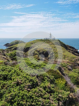 Strumble Head Lighthouse on Ynys Meicel with white clouds, Pembrokeshire, Wales