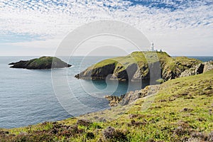 Strumble Head Lighthouse on Ynys Meicel with white clouds, Pembrokeshire, Wales