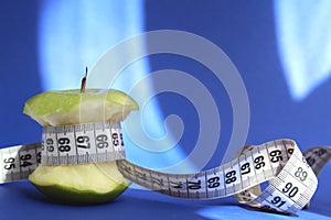 Stub of a green apple with a centimeter tape on a blue background