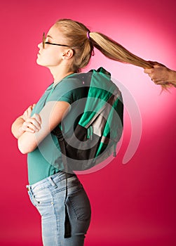 Stubborn, angry schoolgirl resisting to go to school.