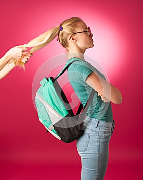 Stubborn, angry schoolgirl resisting to go to school.