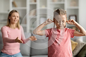 Stubborn Child. Offended little girl covering ears, not to hear mother's scolding