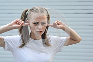 Stubborn, headstrong teen age girl, with fingers in her ear, she does not want to listen. Education problems