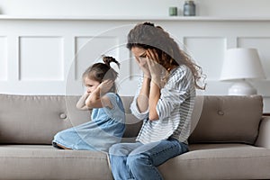 Stubborn spoiled little girl covering ears, ignoring hopeless upset mother