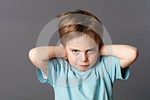 Stubborn young kid teasing, covering closed ears, ignoring parents photo