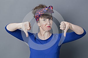 Stubborn young woman with thumbs down sulking for childish disappointment