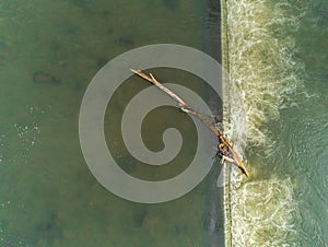 Stucked big pine log in the flowing river aerial drone top down view
