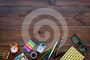 Student accessories. School or student`s stationery mockup with glasses, alarm clock, notebook on dark wooden background