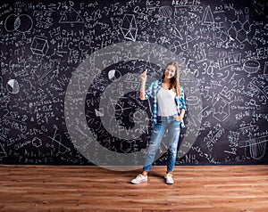 Student against a big blackboard with mathematical symbols