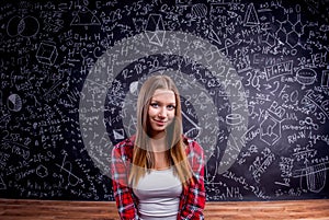 Student against a big blackboard with mathematical symbols