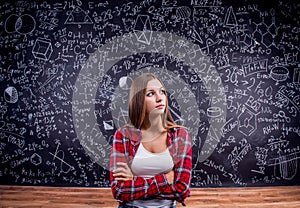 Student against a big blackboard with mathematical symbols