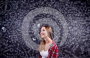 Student against a big blackboard with mathematical symbols