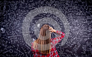 Student against a big blackboard with mathematical symbols