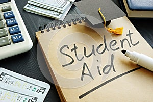 Student aid sign with small graduation cap and money.