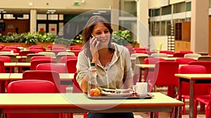 Student answering her phone while having lunch in canteen