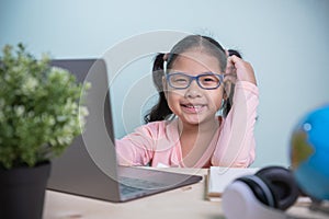 Student Asian kids girls wearing glasses smile happy looking at the camera learning from home in the room personal. Concept
