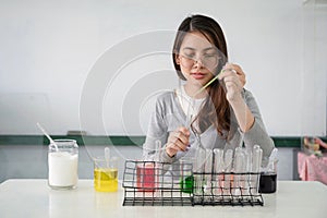 Student asian woman making analyzing and mixing liquid in test tube, color beaker at experiment laboratory in sciense class