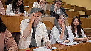 A student is asked a question at a lecture, the guy does not know the answer. A group of students is engaged in a